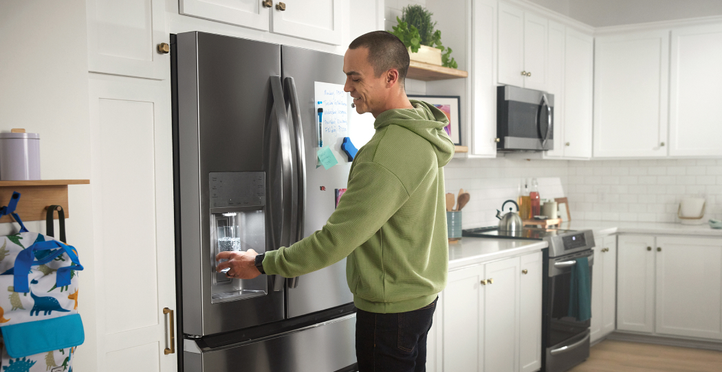 a photo of a man getting water from his dark gray, stainless steel, built-in refrigerator